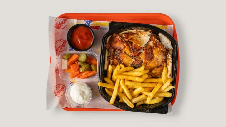 Tasty fast food tray featuring chicken, fries, pickles, and dips on an orange tray. Perfect for food articles.