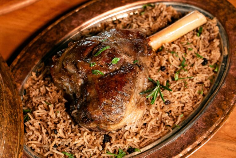 Juicy roasted lamb shank served on aromatic basmati rice garnished with herbs.