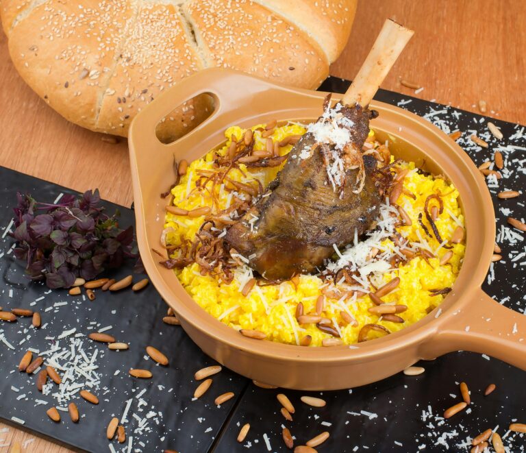Deliciously plated lamb shank atop saffron risotto garnished with herbs and pine nuts.